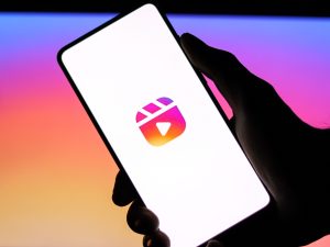 A hand holding a smartphone displaying a logo on a colorful background